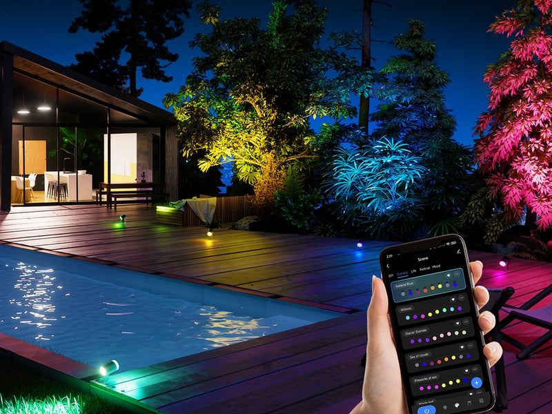 Smart outdoor spotlights lighting pool and backyard landscape with RGB colors, controlled via mobile app