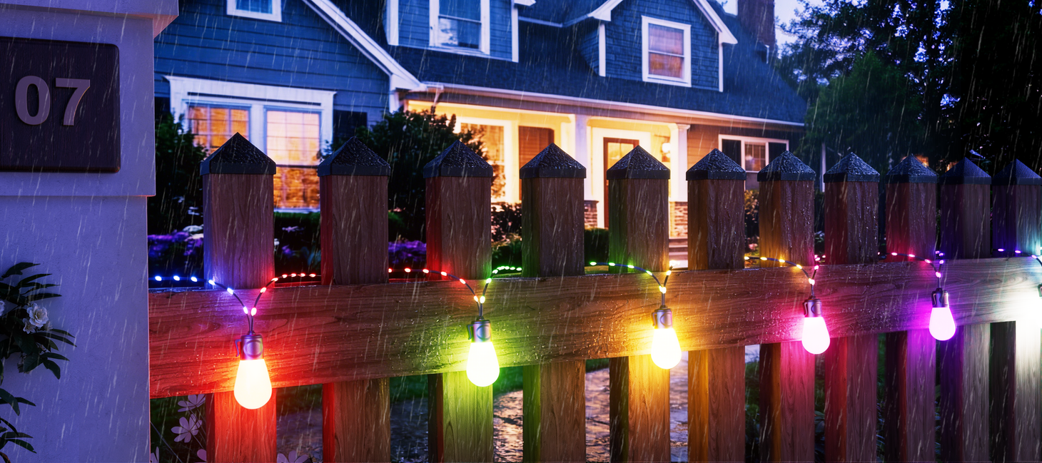Waterproof smart outdoor string lights installed along fence in rainy weather