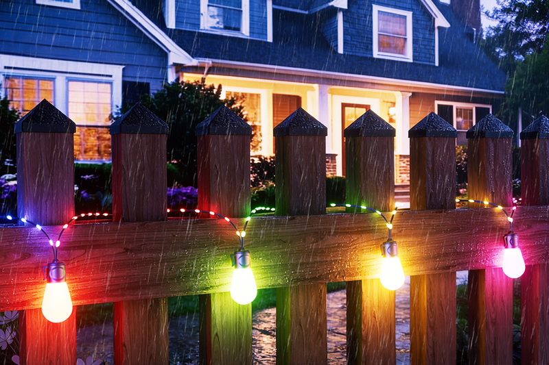 Waterproof smart outdoor string lights installed along fence in rainy weather