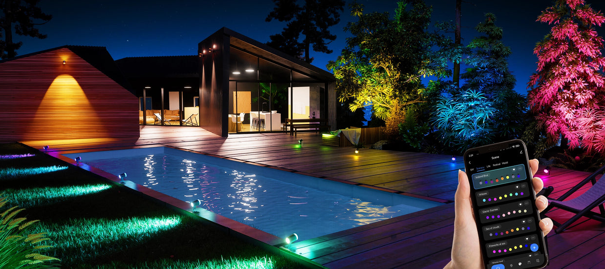 Smart outdoor spotlights lighting pool and backyard landscape with RGB colors, controlled via mobile app